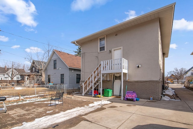 rear view of property featuring a patio, stairway, brick siding, stucco siding, and fence