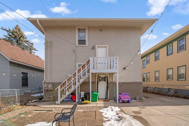 back of house featuring fence, stairs, and stucco siding