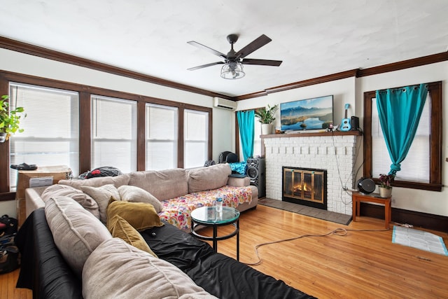 living room with crown molding, an AC wall unit, a brick fireplace, wood finished floors, and a ceiling fan