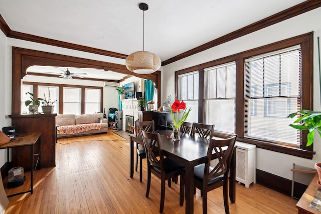 dining space with ornamental molding, an AC wall unit, a wealth of natural light, and light wood-style floors