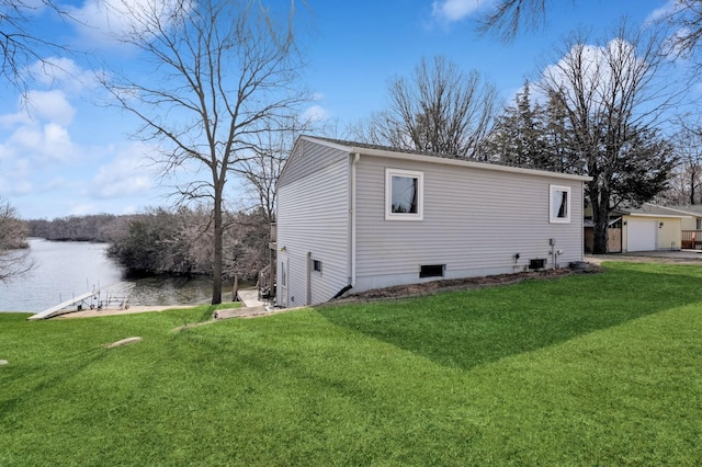view of side of home featuring an outbuilding, a water view, and a yard