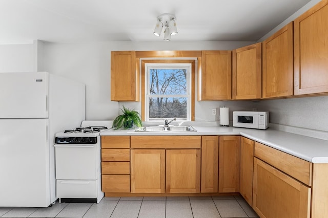 kitchen featuring a sink, light countertops, light tile patterned floors, and white appliances