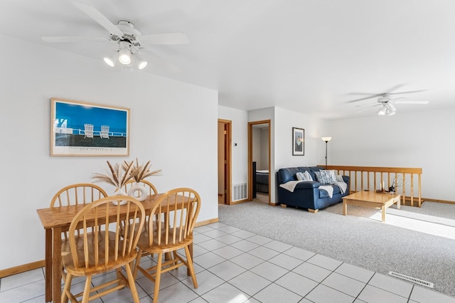 dining room with a ceiling fan, baseboards, and light carpet