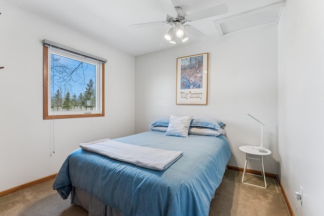 carpeted bedroom featuring baseboards, attic access, and a ceiling fan