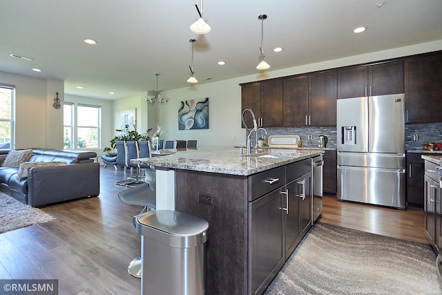 kitchen featuring dark brown cabinetry, open floor plan, stainless steel fridge, and dark wood-style floors