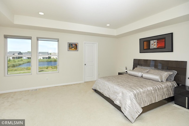 bedroom featuring light carpet, recessed lighting, baseboards, and a tray ceiling