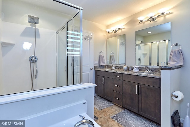 bathroom featuring a sink, a stall shower, and double vanity