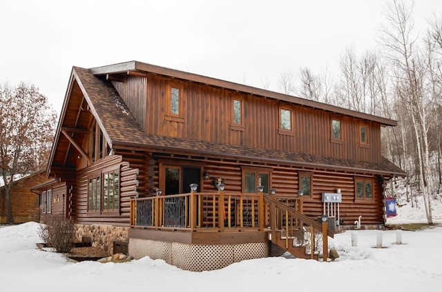 snow covered property with log siding and roof with shingles