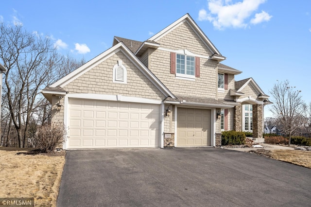 view of front of property featuring aphalt driveway, an attached garage, and stone siding