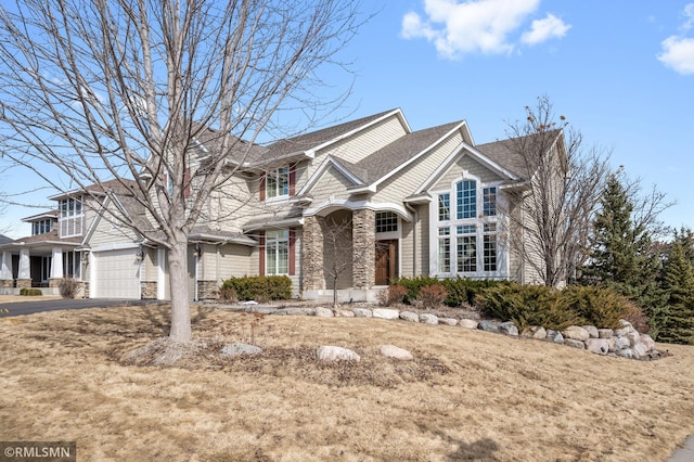 view of front facade featuring aphalt driveway, a garage, stone siding, and a shingled roof