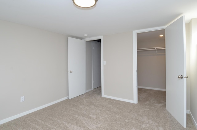 unfurnished bedroom featuring a walk in closet, carpet floors, and baseboards