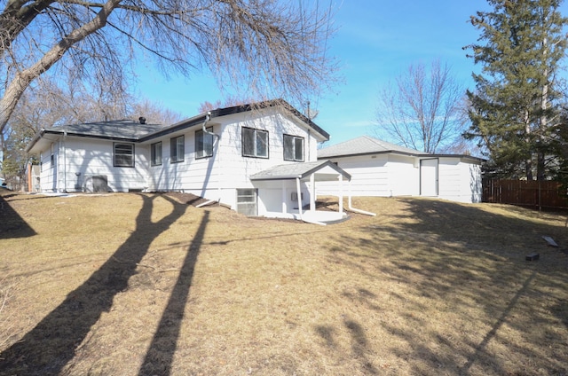 back of house featuring a yard, an outdoor structure, and fence