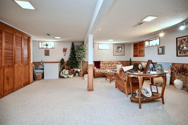 carpeted living area featuring visible vents, wainscoting, and a textured ceiling