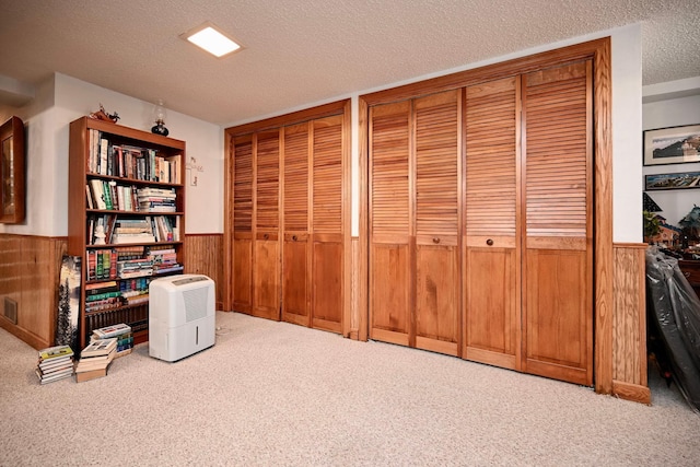 office area with visible vents, a wainscoted wall, wood walls, a textured ceiling, and carpet flooring