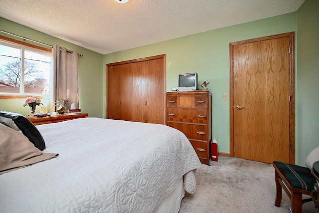 carpeted bedroom with a closet, a textured ceiling, and baseboards