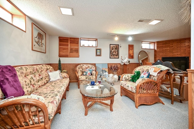 living area with a wainscoted wall, carpet floors, a textured ceiling, and a fireplace