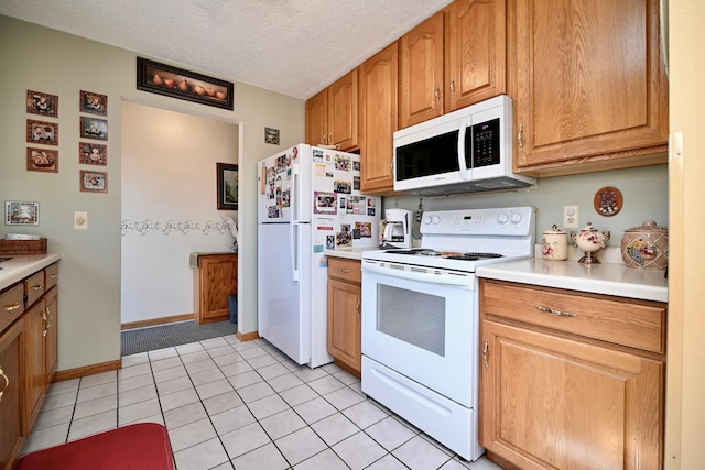 kitchen with baseboards, light countertops, light tile patterned flooring, white appliances, and a textured ceiling