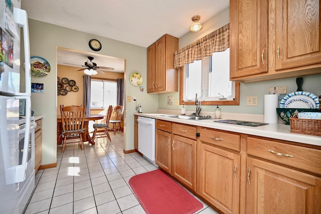 kitchen featuring a sink, light countertops, light tile patterned floors, dishwasher, and ceiling fan