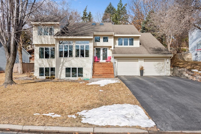 tri-level home with fence, a shingled roof, french doors, a garage, and aphalt driveway