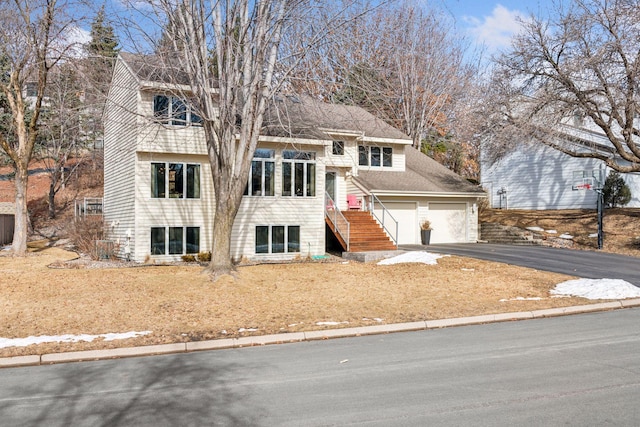 split level home featuring stairs, aphalt driveway, and a shingled roof