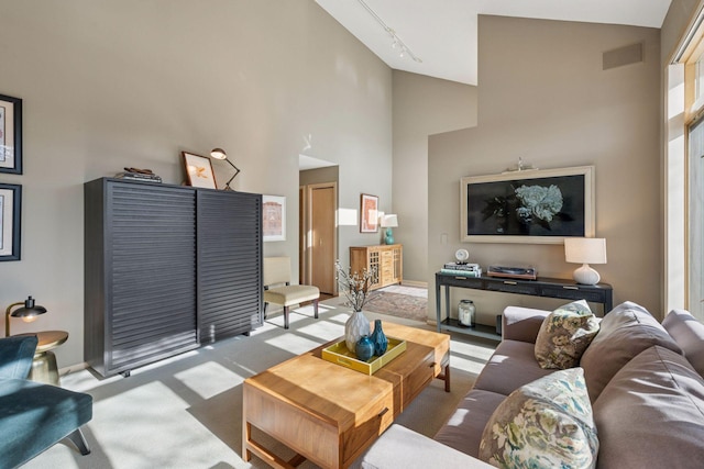 living area with visible vents, carpet floors, a towering ceiling, and track lighting