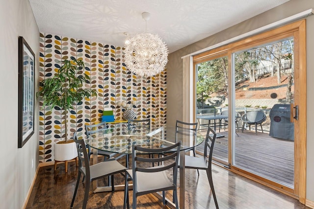 dining area featuring baseboards, a notable chandelier, wood finished floors, and a textured ceiling