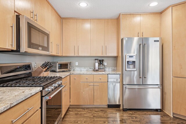 kitchen with stainless steel appliances, light stone countertops, dark wood-style floors, and light brown cabinets