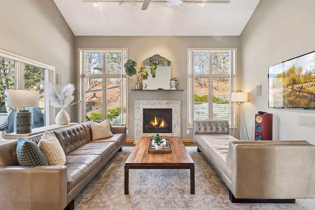 living area featuring ceiling fan, a fireplace, and vaulted ceiling