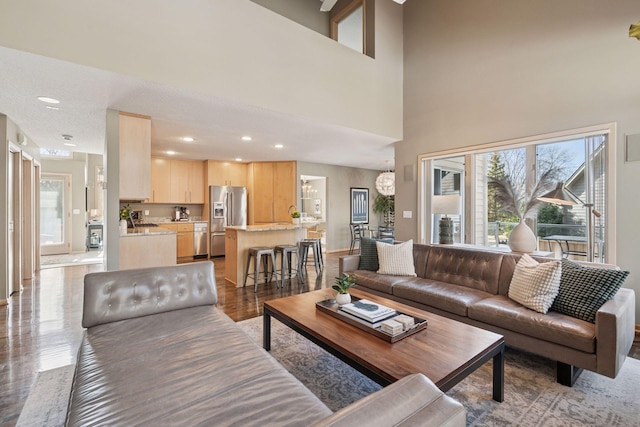 living area with an inviting chandelier, plenty of natural light, recessed lighting, and wood finished floors