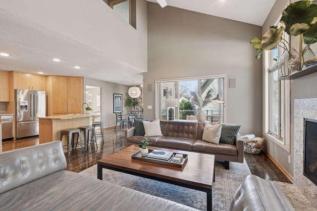 living room with wood finished floors, baseboards, a high end fireplace, and a chandelier