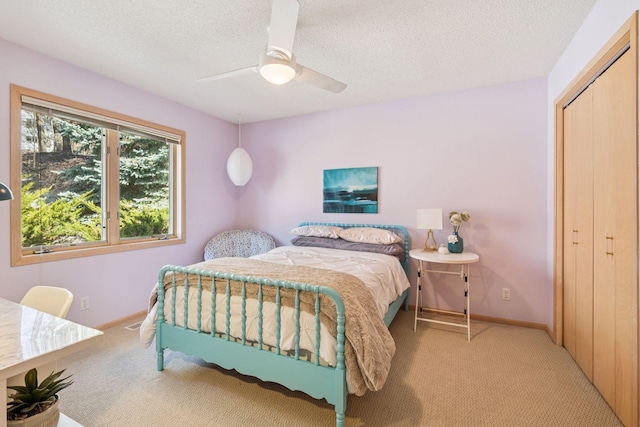 bedroom featuring a ceiling fan, light colored carpet, baseboards, and a textured ceiling