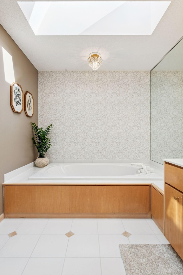 bathroom with tile patterned flooring, a garden tub, a skylight, and vanity