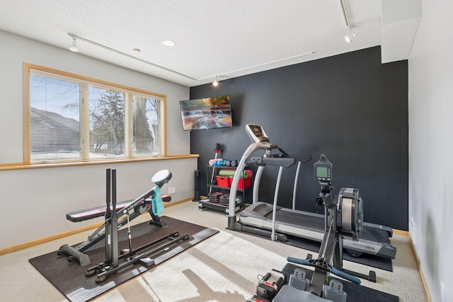 workout room featuring rail lighting, a textured ceiling, baseboards, and carpet floors