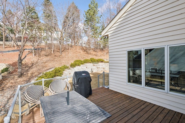 wooden terrace featuring area for grilling and outdoor dining space