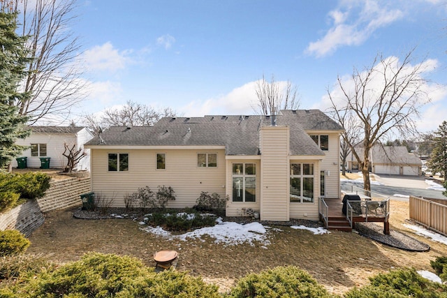 back of house with a deck, fence, roof with shingles, and a chimney