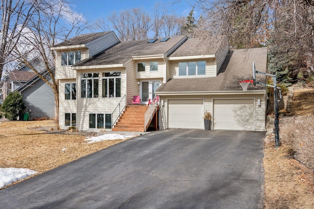 split level home featuring aphalt driveway and a shingled roof