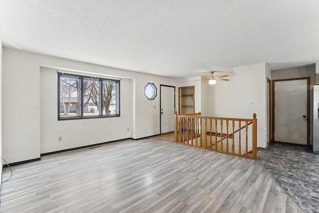 entryway with ceiling fan, wood finished floors, baseboards, and a textured ceiling