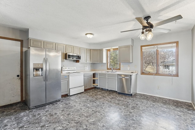 kitchen featuring a ceiling fan, a sink, a textured ceiling, stainless steel appliances, and light countertops