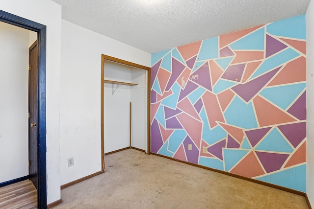 unfurnished bedroom with a closet, baseboards, a textured ceiling, and carpet flooring