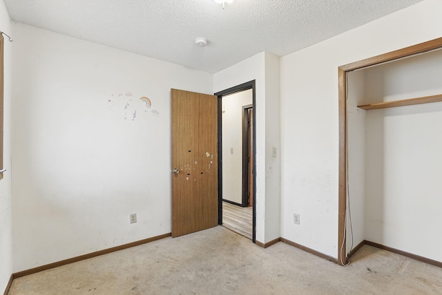 unfurnished bedroom featuring a closet, carpet floors, a textured ceiling, and baseboards