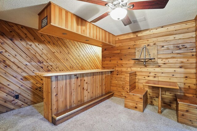 interior space with wooden walls, a ceiling fan, carpet, a sauna, and a textured ceiling