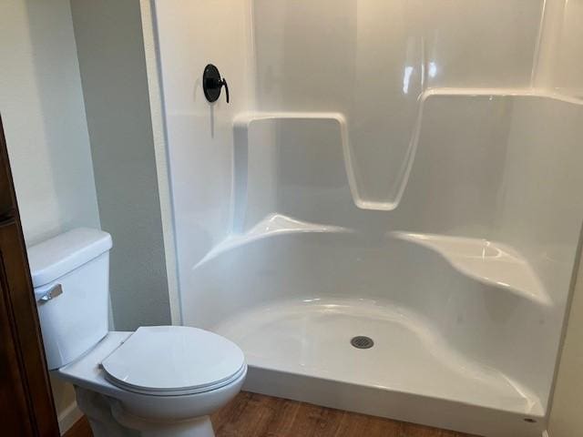 bathroom featuring toilet, wood finished floors, and walk in shower