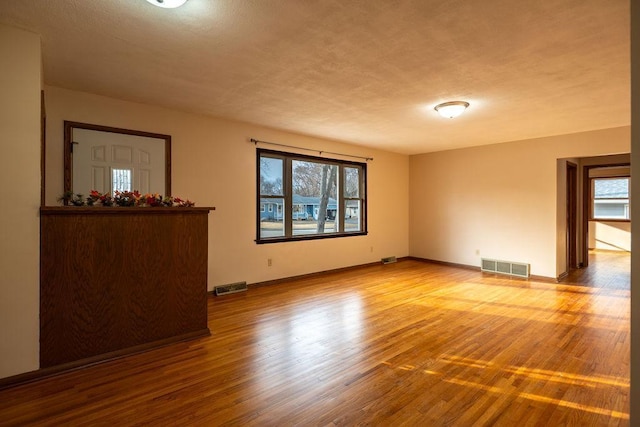 unfurnished room with visible vents, baseboards, and wood finished floors