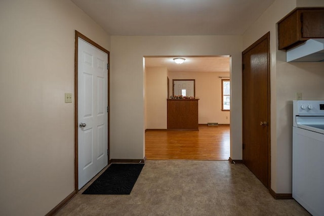 hall with baseboards, washer / clothes dryer, and wood finished floors