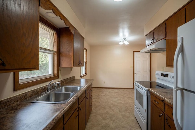 kitchen with under cabinet range hood, a sink, dark countertops, white appliances, and baseboards