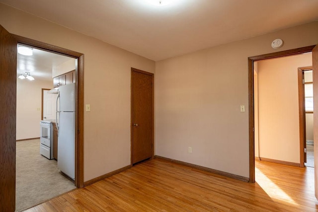 spare room with light wood finished floors and baseboards