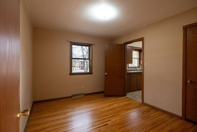 unfurnished room featuring baseboards, visible vents, and light wood-type flooring