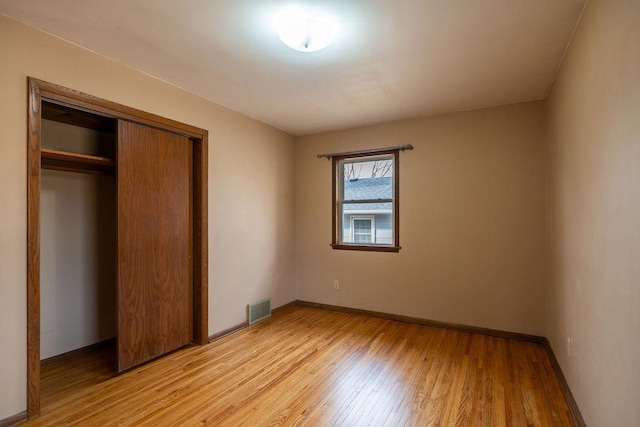 unfurnished bedroom with visible vents, baseboards, a closet, and light wood-style flooring