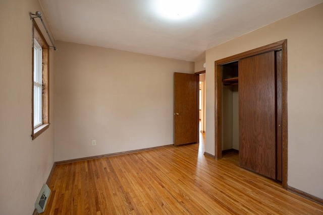 unfurnished bedroom featuring visible vents, light wood-type flooring, a closet, and baseboards