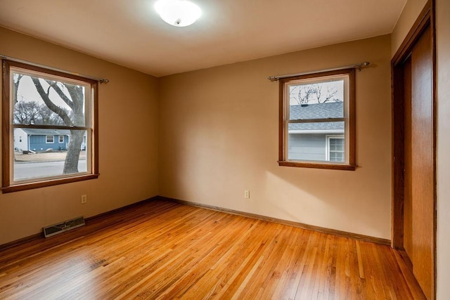 unfurnished bedroom featuring visible vents, multiple windows, light wood-type flooring, and baseboards